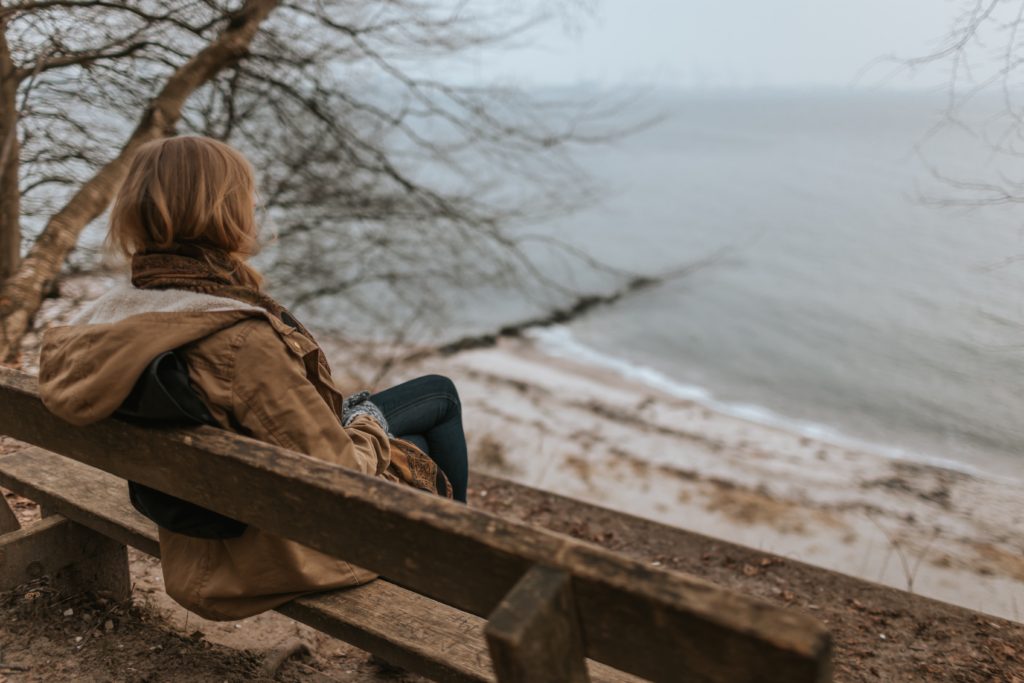 Woman sitting on bench near water grieving